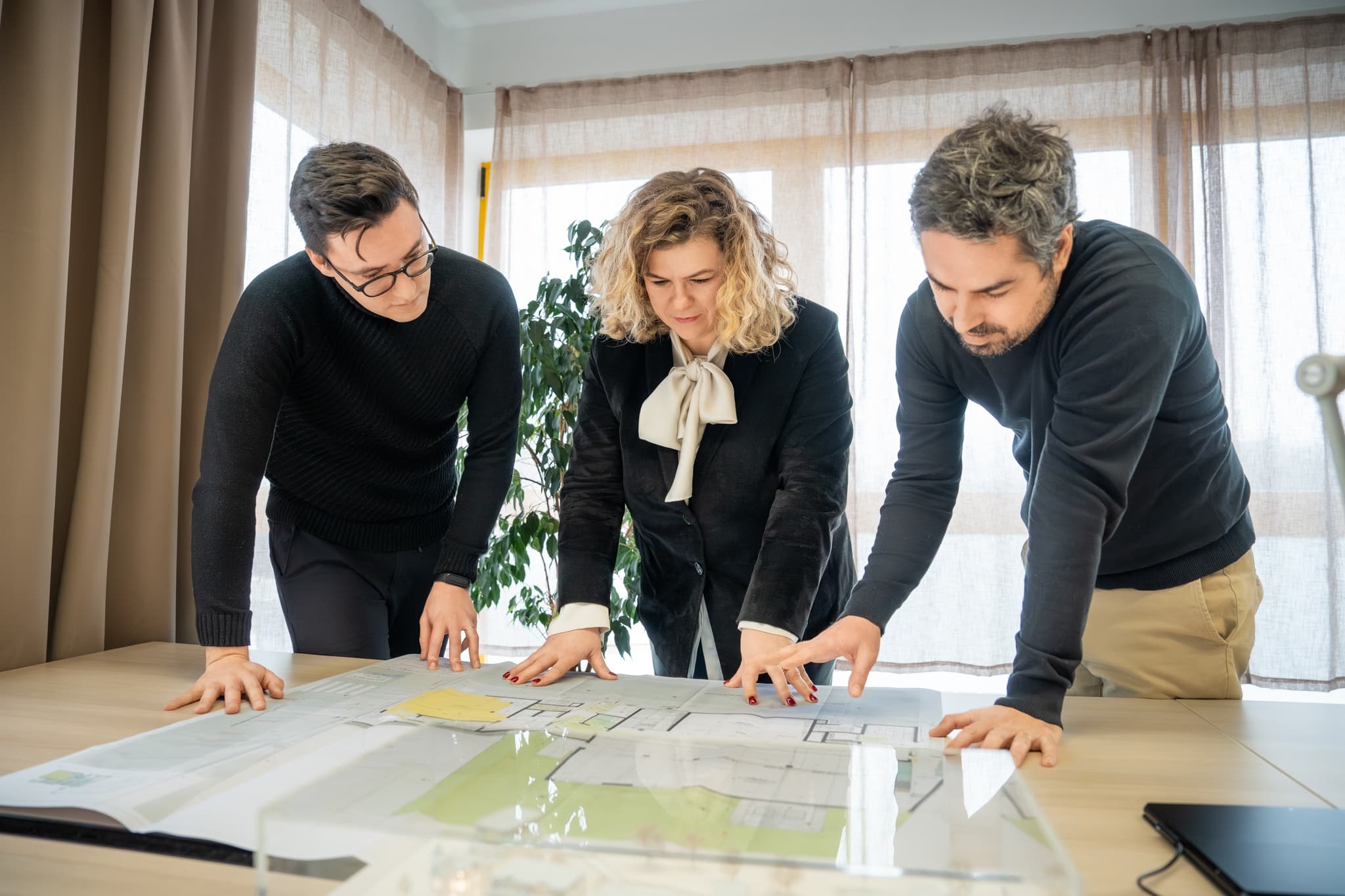 Trois architectes d'ACOM autour d'un plan, atelier de Strassen.